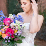 The bride poses with a vibrant bouquet of pink, yellow, and purple blooms during a spring wedding at The Factory at Walton Mill in Monroe, Georgia.