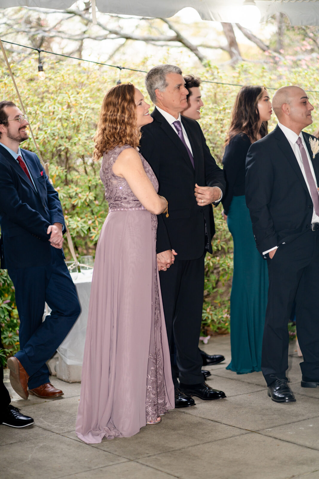 The bride’s parents hold hands and smile proudly while watching wedding speeches at The 173 Carlyle House in Norcross, GA