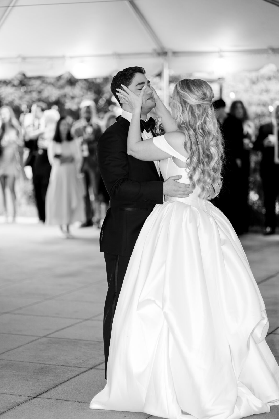 Emotional black and white photo of bride touching groom’s face during first dance