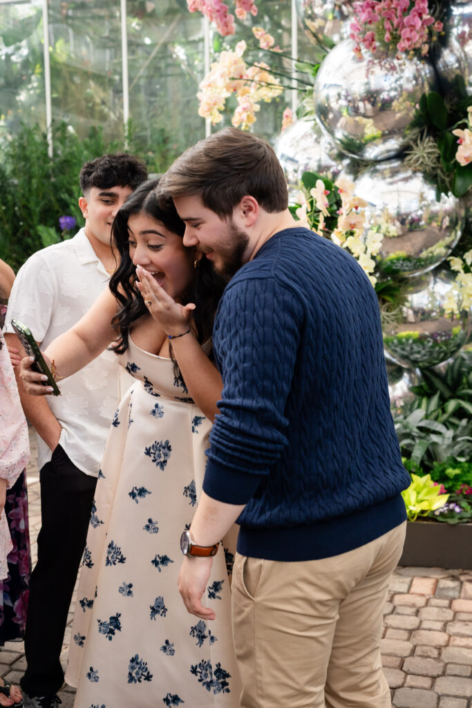 couple sharing joyful announcement of engagement with friend over video call