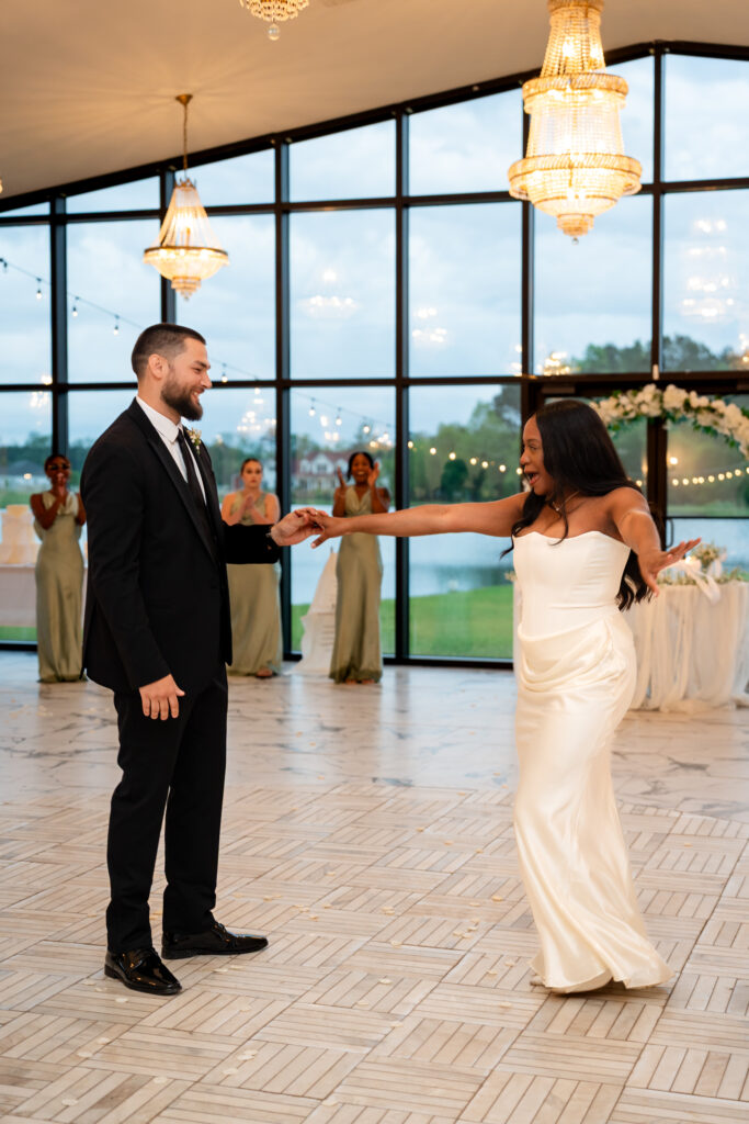 Bride playfully reaches for her groom as their wedding party cheers in the background.