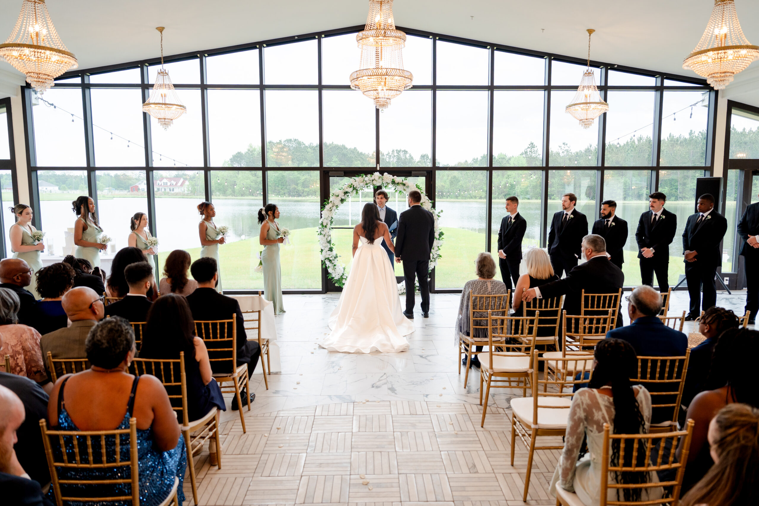 Indoor wedding ceremony with large glass windows overlooking the garden landscape