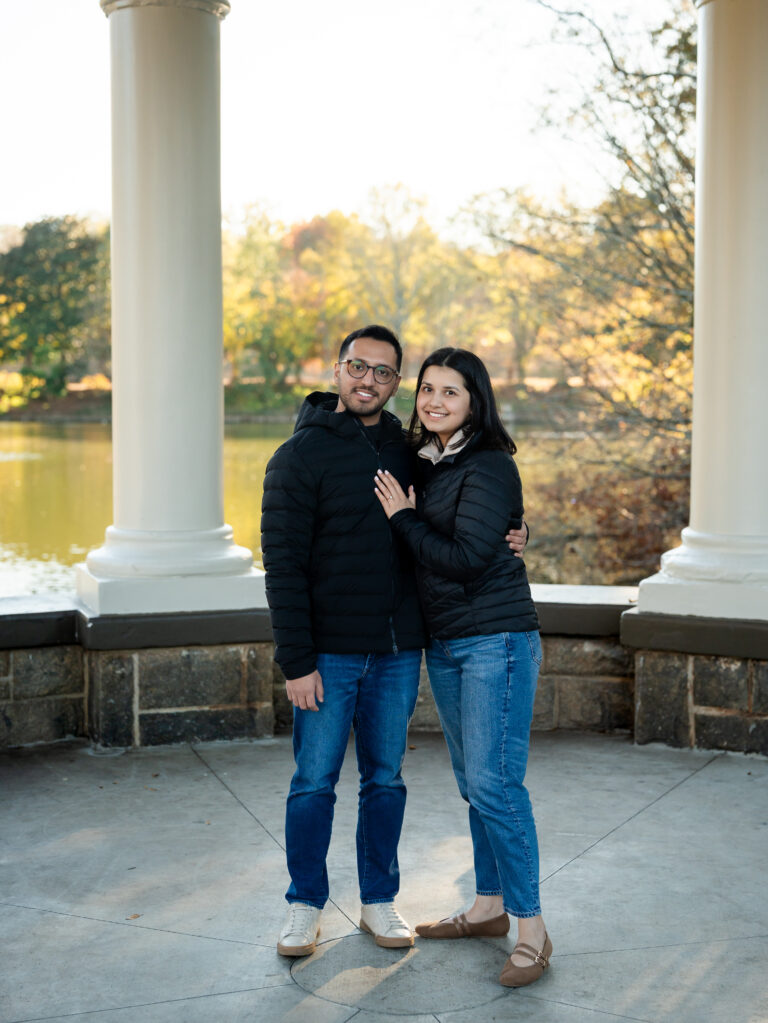 Couple smiling together in front of the Clara Meer Lake gazebo at Piedmont Park after a surprise proposal.