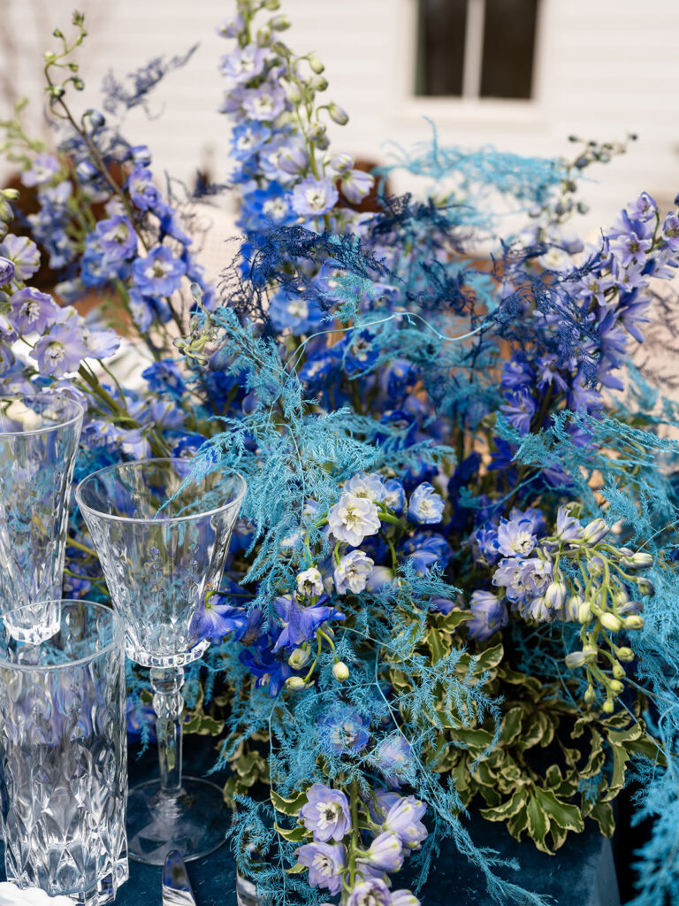 Bright blue blooms next to crystal glasses on a beautiful table scape for an example of the average cost of wedding in Georgia.