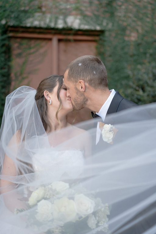 Bride and groom kiss with veil blowing in the breeze after they get married in Georgia