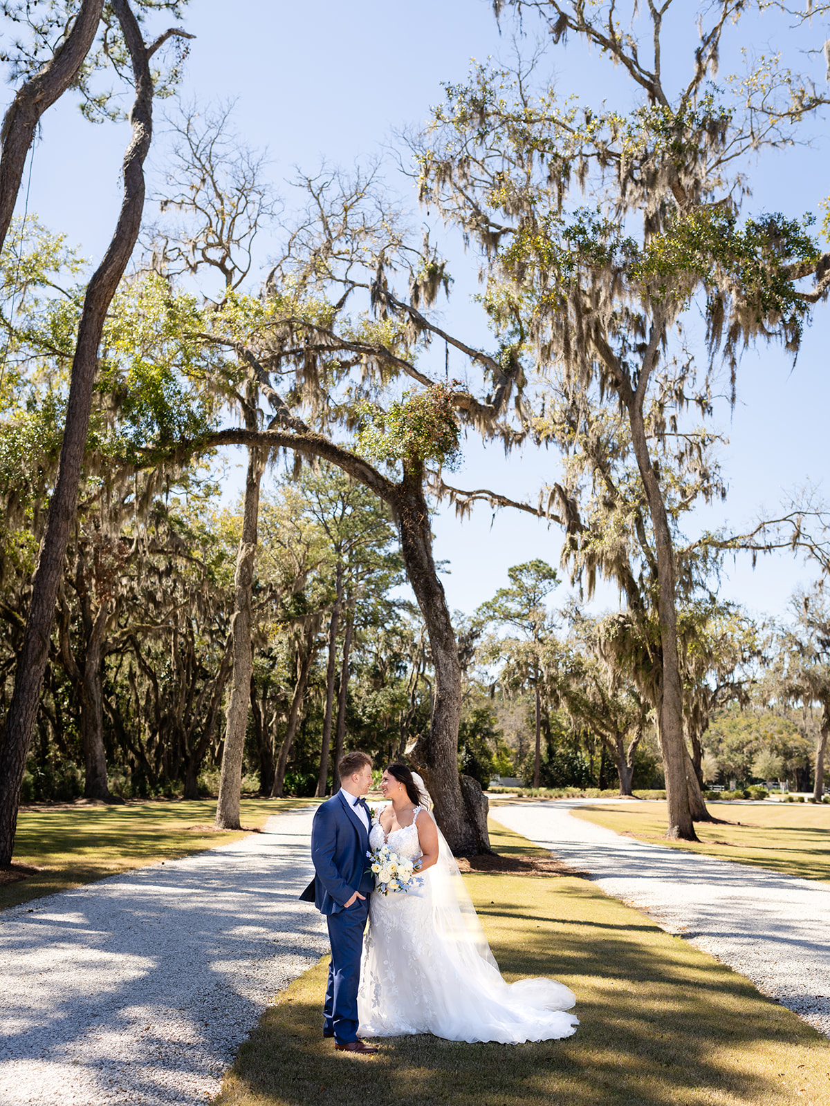 Bride and groom sharing a portrait beneath moss-covered oaks as part of their wedding photography package in Georgia.