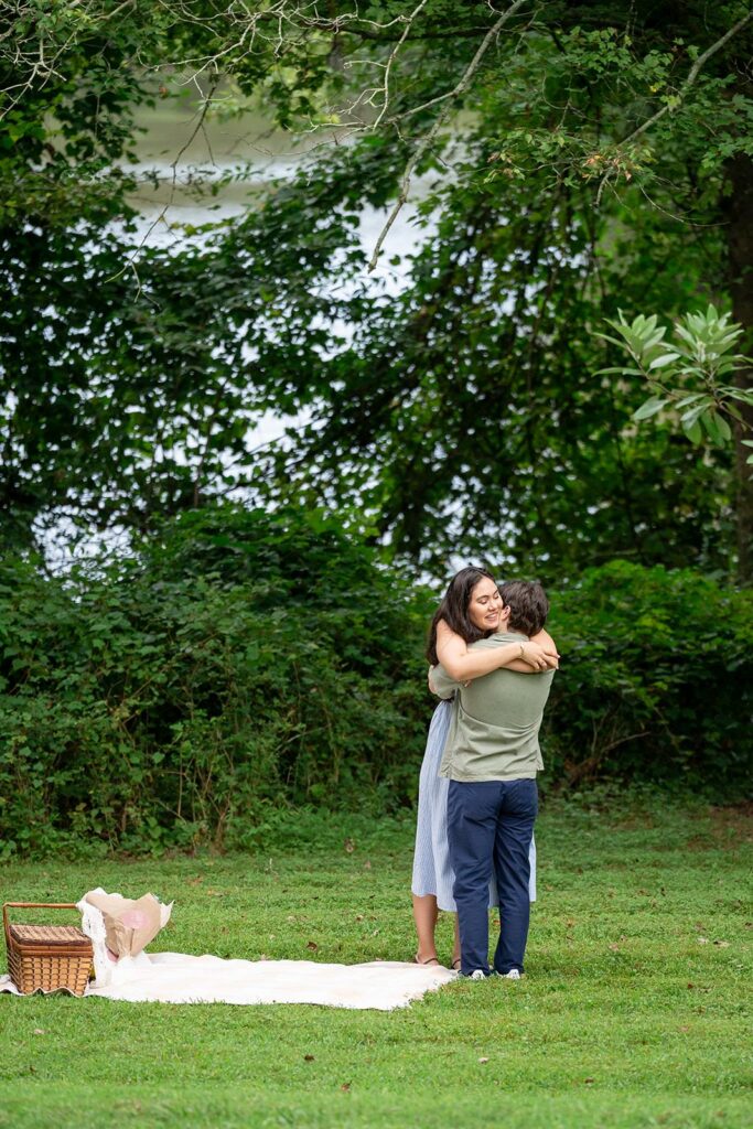 Couple embracing during a picnic engagement session at one of the best places to take engagement photos in Georgia.