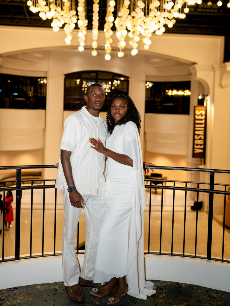 Couple posing beneath the chandeliers inside Château Élan, one of the most elegant places to take engagement photos in Georgia.