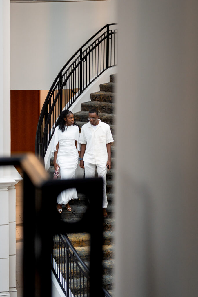 Couple walking down the grand staircase during an engagement session at Château Élan, one of the best places to take engagement photos in Georgia.